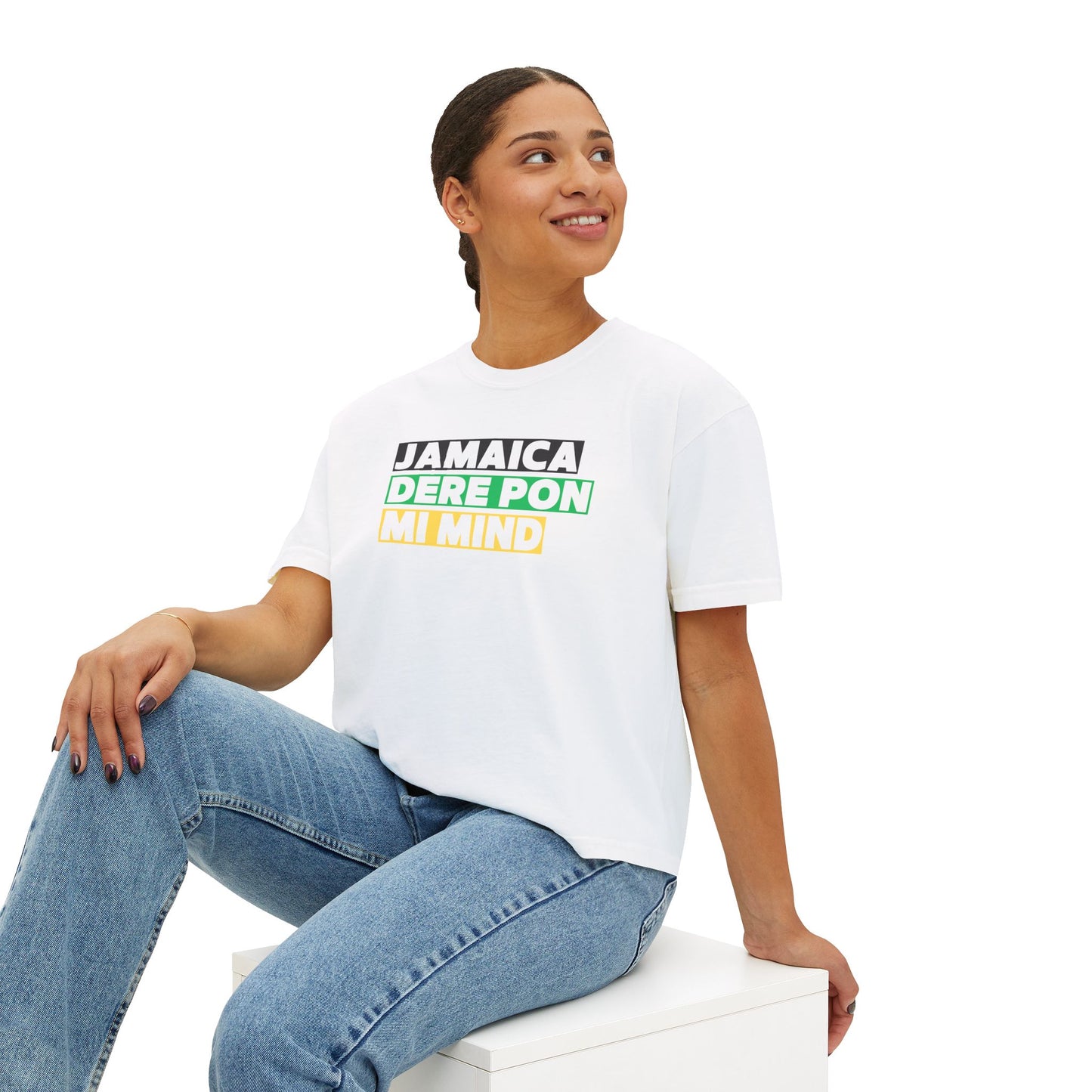 Woman sitting down wearing white Cropped Graphic T-shirt with 'Jamaica Dere Pon Mi Mind' printed in bold text with a Black, Green and Gold Background.